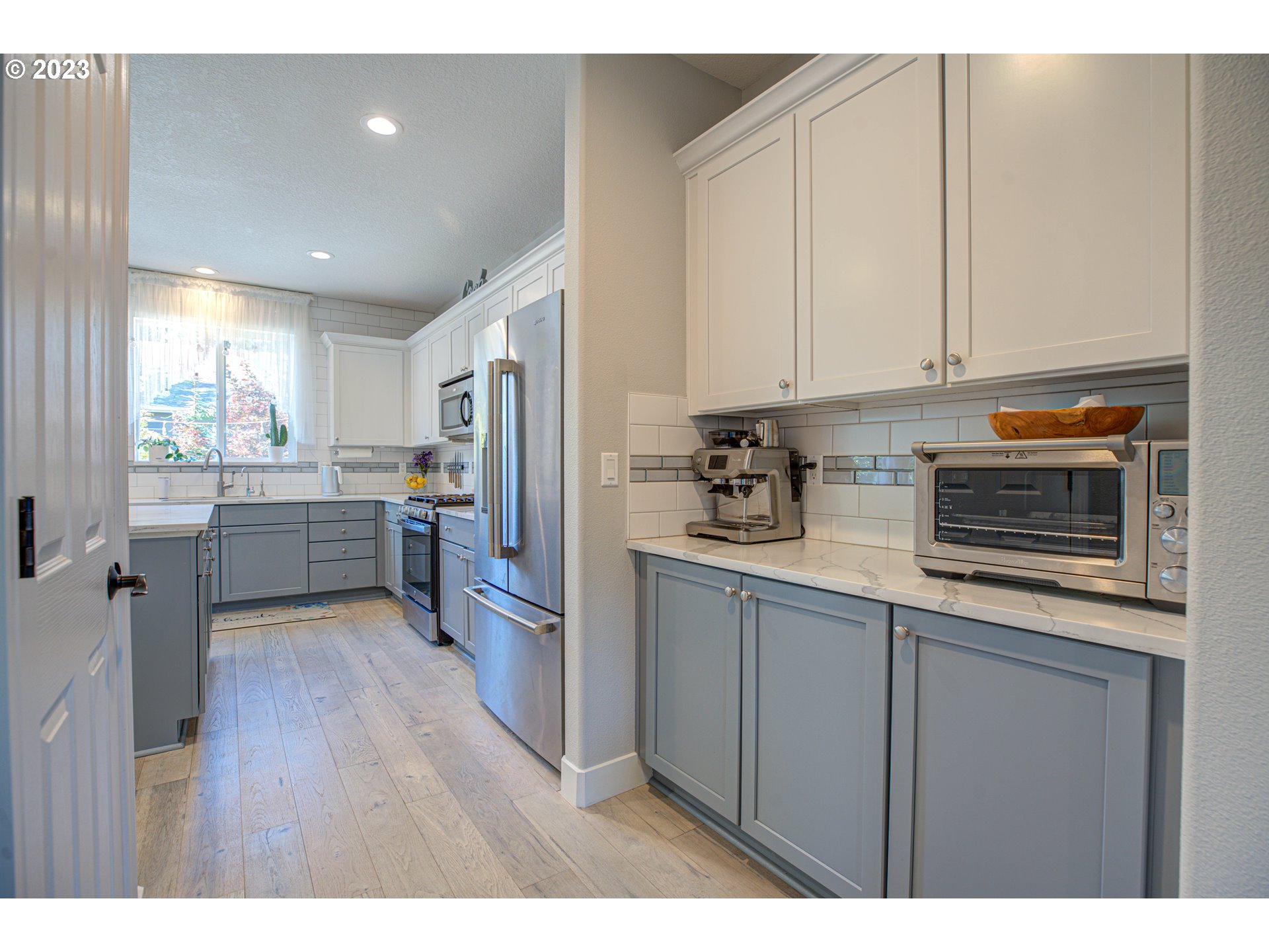 6055 Southeast 28th Street Gresham, OR 97080 - Photo 27 of 48 a kitchen with stainless steel appliances granite countertop a refrigerator a sink dishwasher and white cabinets with wooden floor