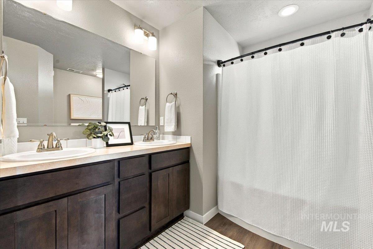 124 South Sunset Point Way Meridian, ID 83642 - Photo 22 of 24 Vanity with an integrated sink and chrome faucet, dark wood-finish cabinetry, a framed window, and wood-finish flooring
