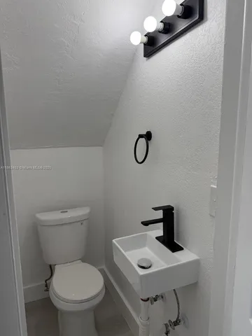 a bathroom with a toilet a sink and mirror