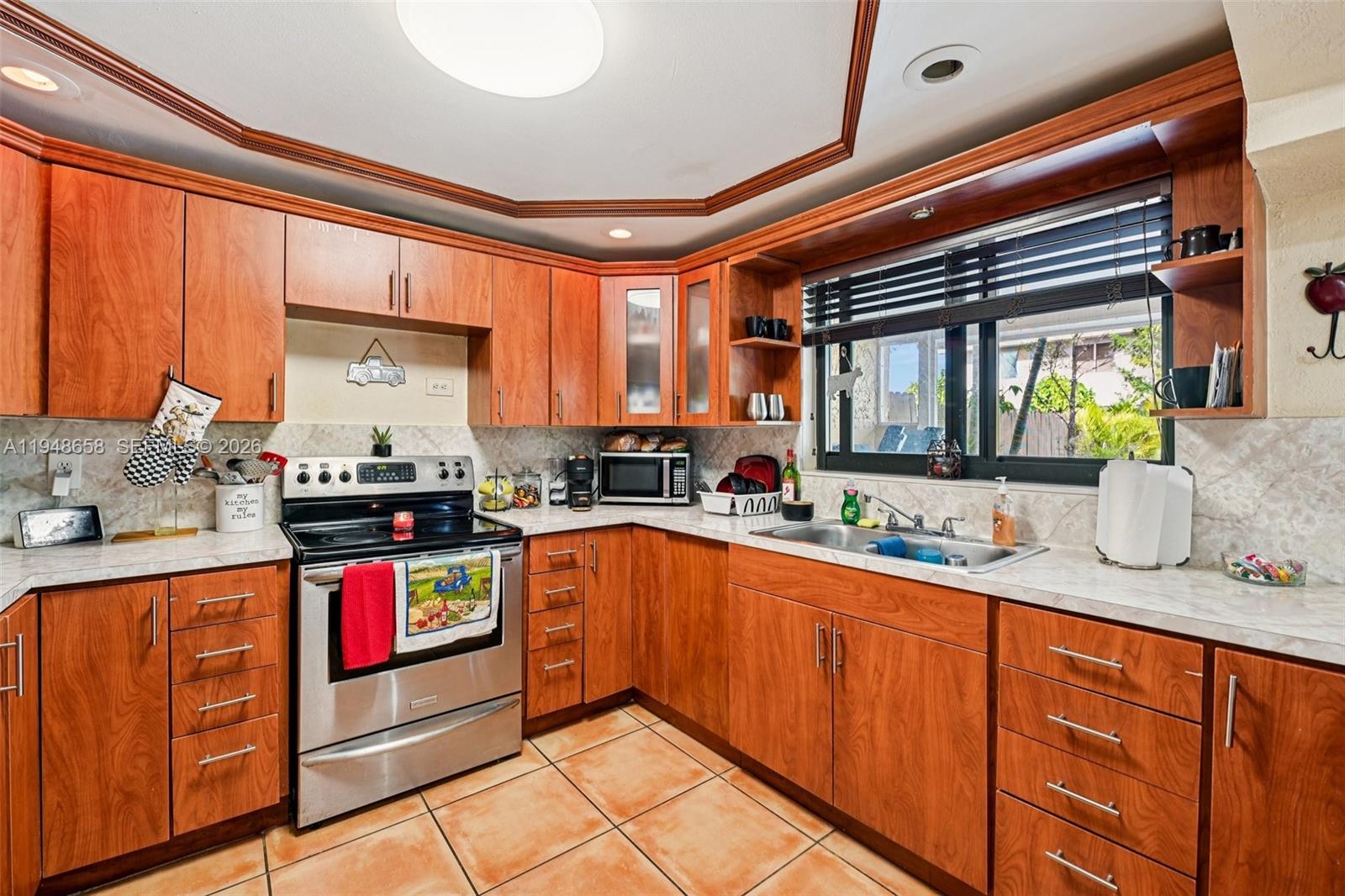 10365 Southwest 11th Terrace, Unit 49B Miami, FL 33174 - Photo 12 of 36 a kitchen with stainless steel appliances granite countertop a sink stove and cabinets