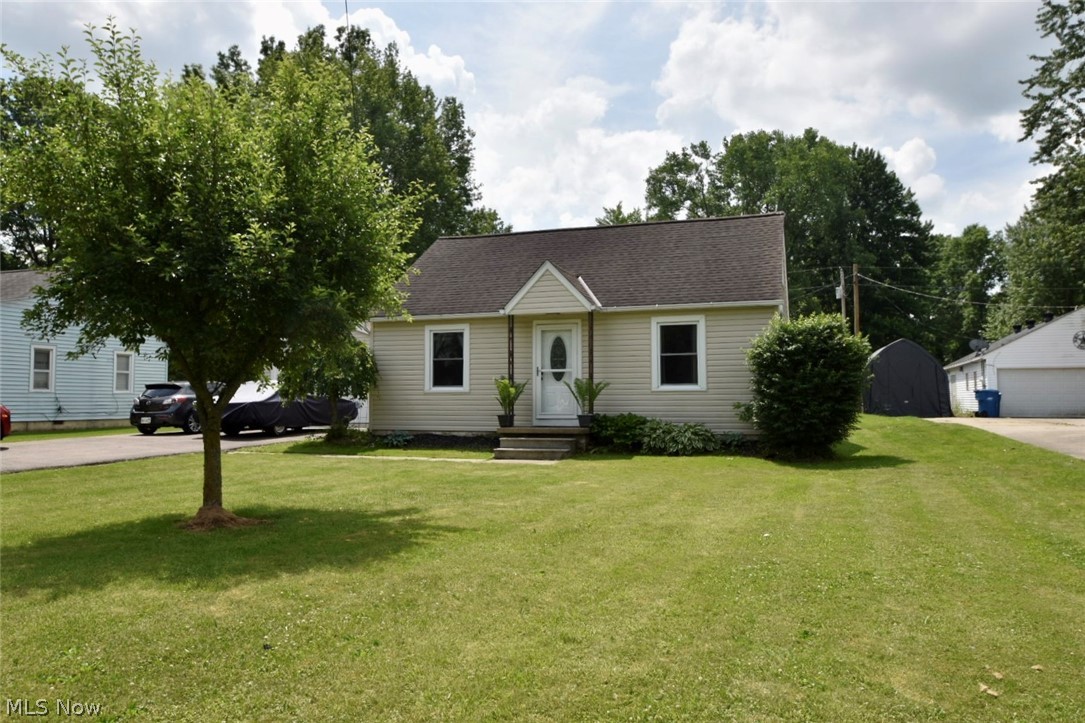 View of front of house with a garage, a front lawn, and an outdoor structure