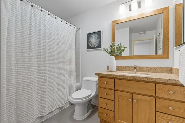 a bathroom with a granite countertop toilet sink and mirror