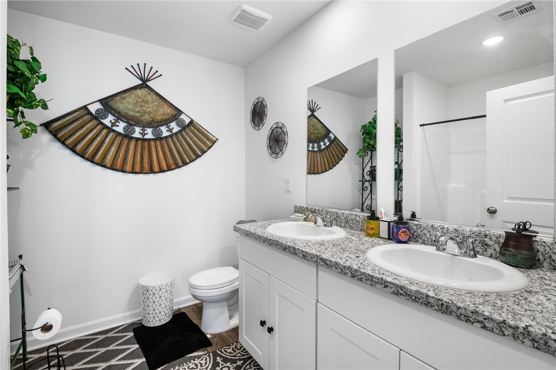 3623 East Andrea Drive Kingman, AZ 86409 - Photo 24 of 40 This bathroom features a double vanity with granite countertops and two sinks, a toilet, and a shower with a clear enclosure