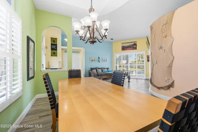 a dining room with wooden floor and chandelier