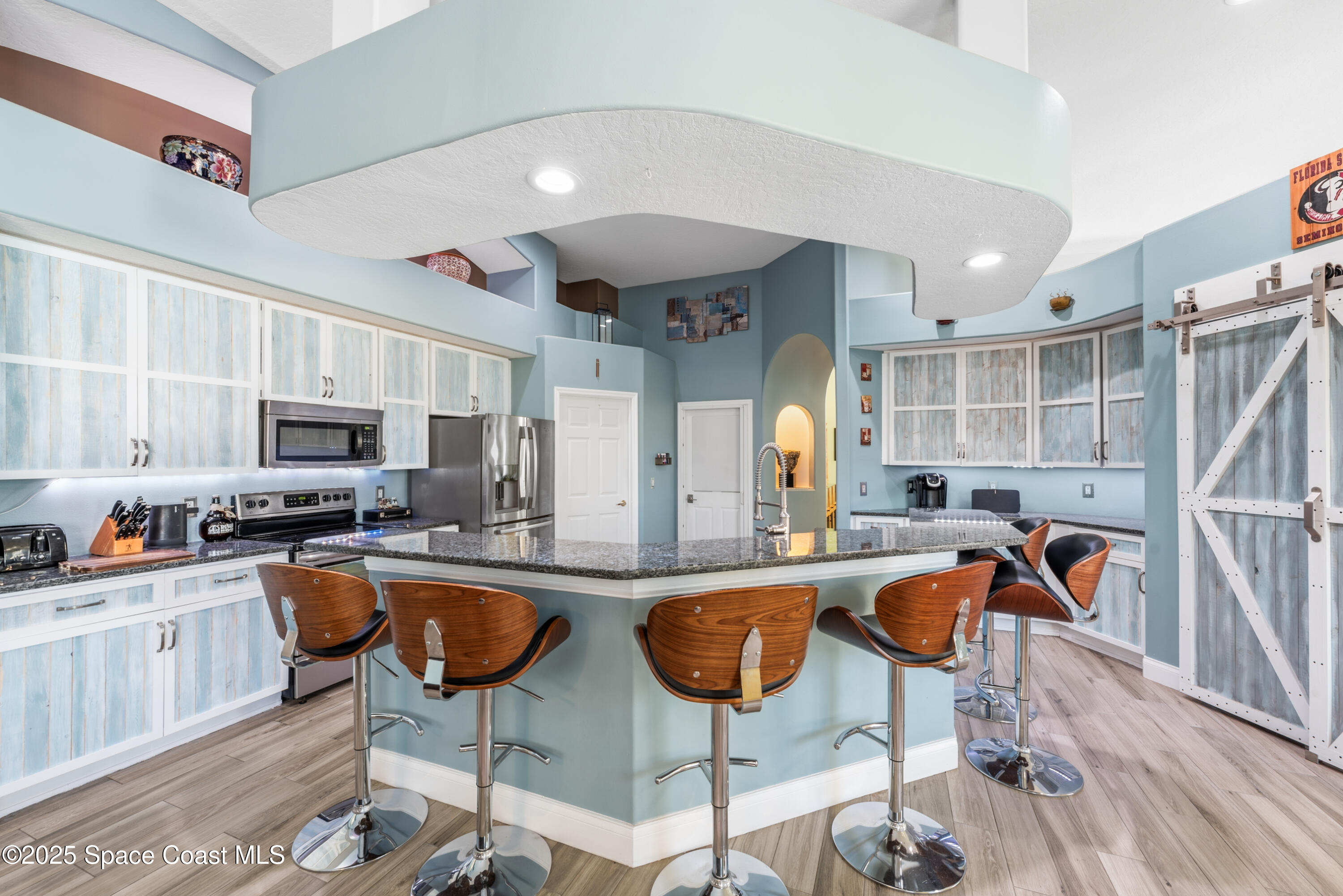 452 Veracruz Boulevard Indialantic, FL 32903 - Photo 17 of 42 a kitchen with stainless steel appliances granite countertop a stove top oven a sink a dining table and chairs with wooden floor