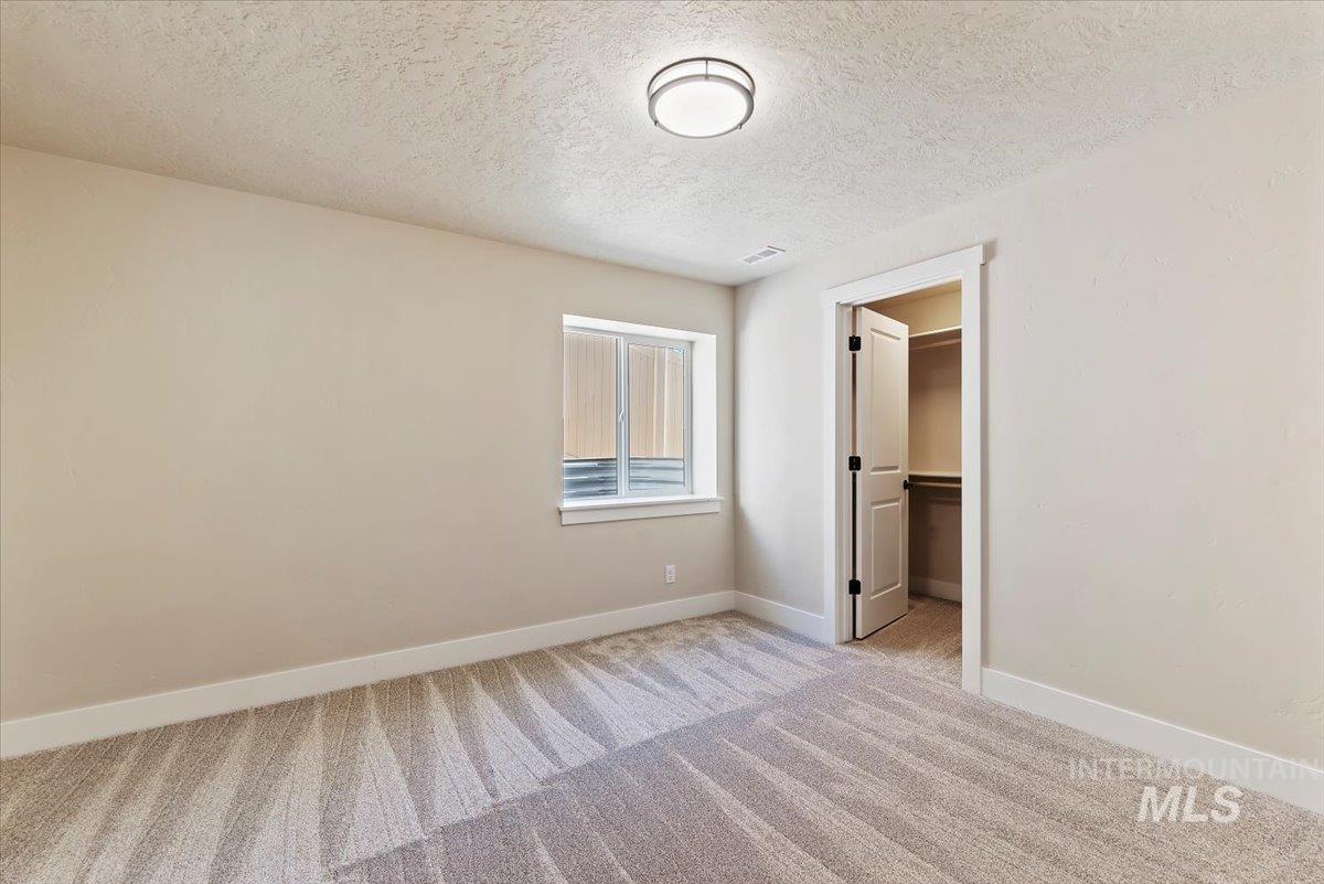 1300 Birch Street Parma, ID 83660 - Photo 14 of 24 Unfurnished bedroom with a spacious closet, light colored carpet, and a textured ceiling
