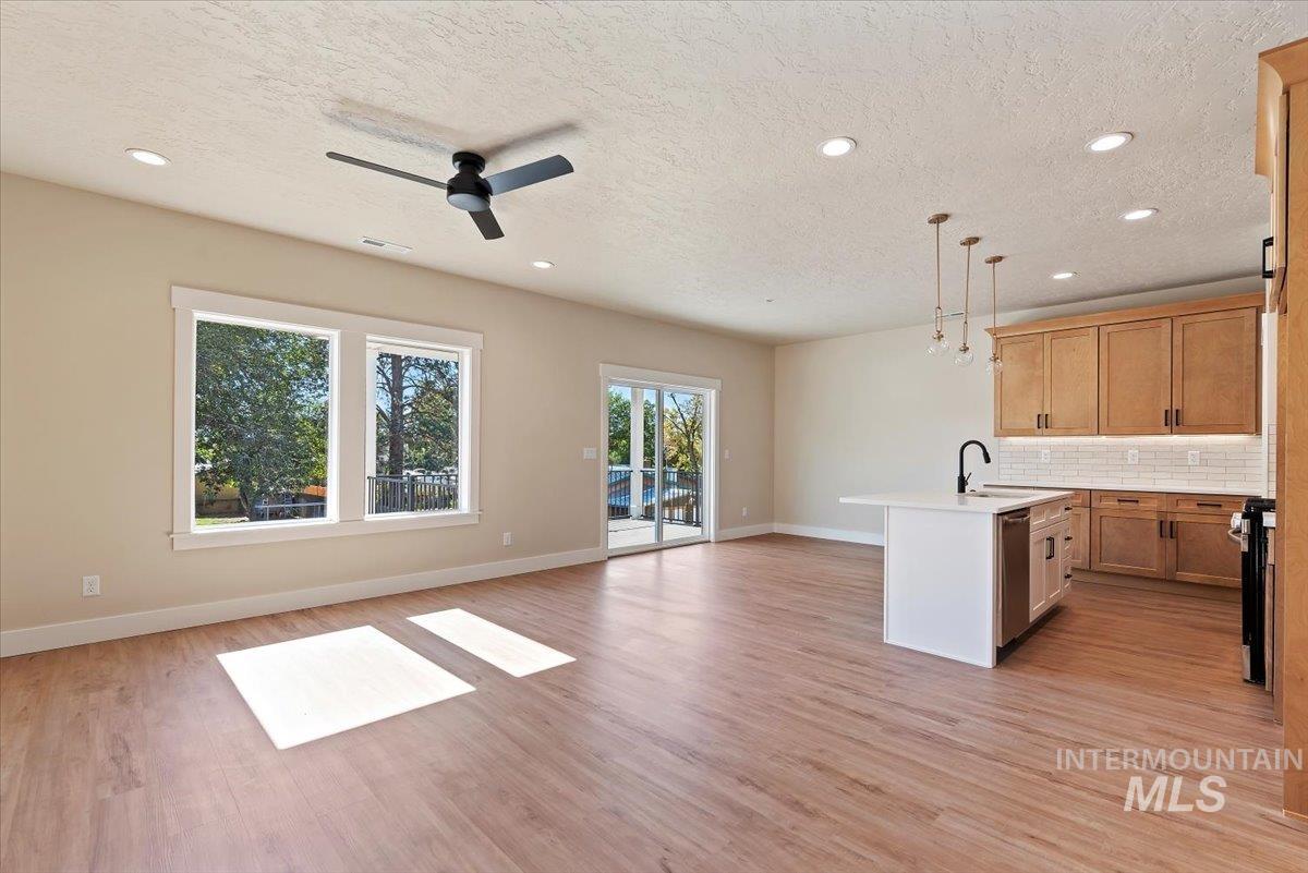 1300 Birch Street Parma, ID 83660 - Photo 24 of 25 Kitchen featuring open floor plan, decorative backsplash, a textured ceiling, recessed lighting, and light wood finished floors