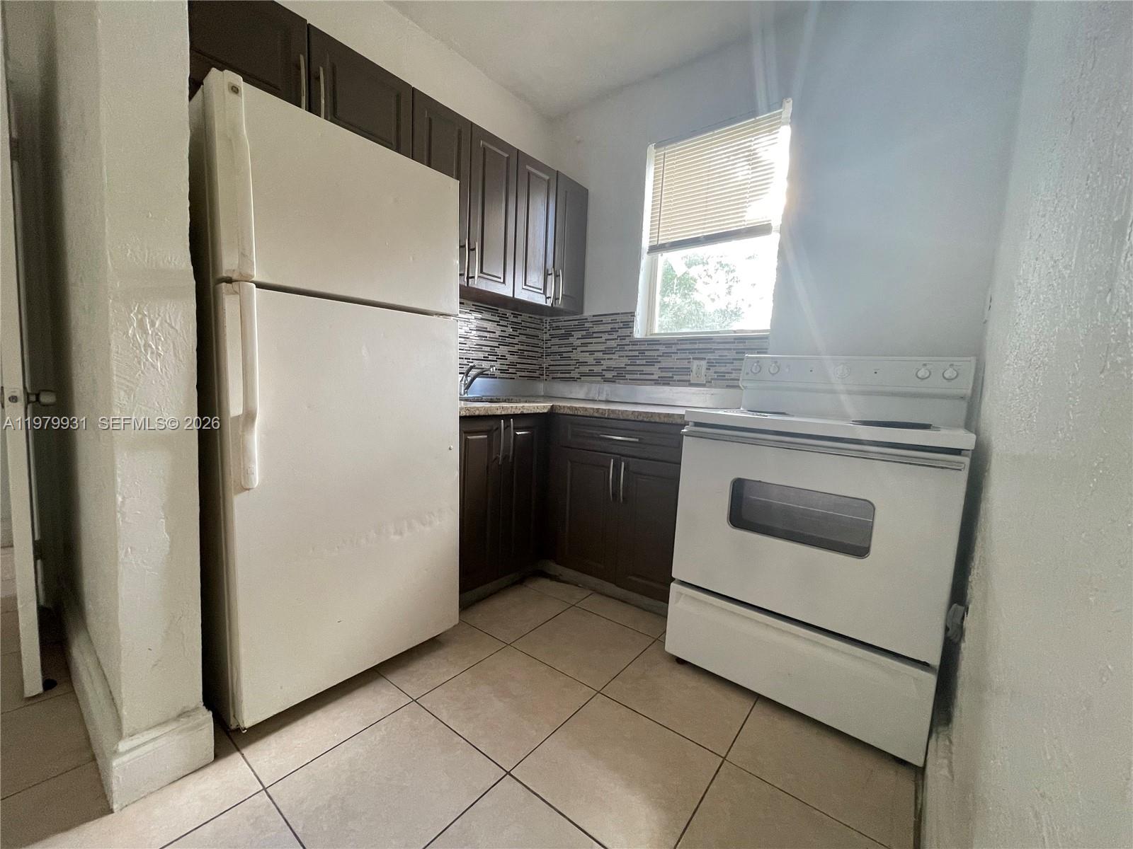 1060 Northwest 47th Street, Unit 5 Miami, FL 33127 - Photo 4 of 19 a kitchen with white cabinets and white appliances