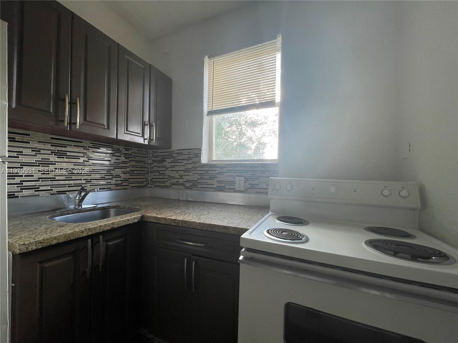 1060 Northwest 47th Street, Unit 5 Miami, FL 33127 - Photo 6 of 19 a view of a kitchen with a sink a window and cabinets