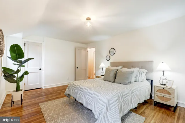 a bedroom with a bed potted plants with the wooden floor