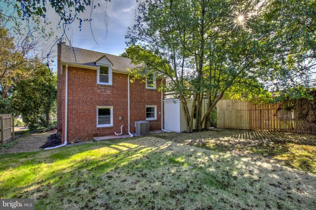 a view of a brick house with a large tree and a yard