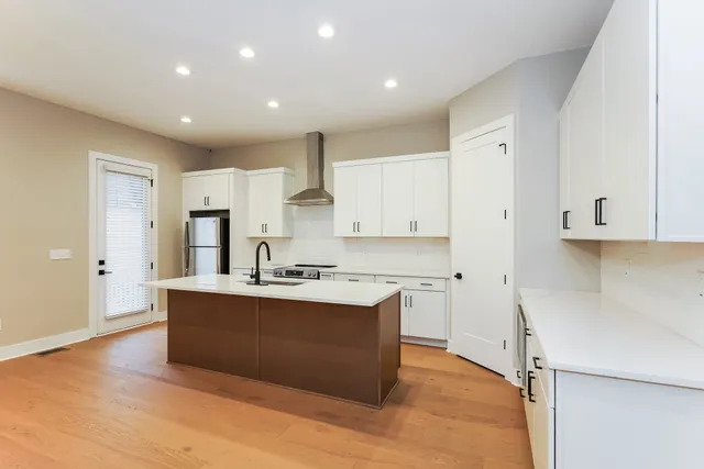 a large kitchen with stainless steel appliances a sink a stove a refrigerator and cabinets