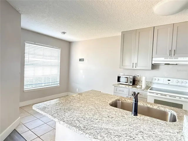 a kitchen with granite countertop a sink stove and white cabinets