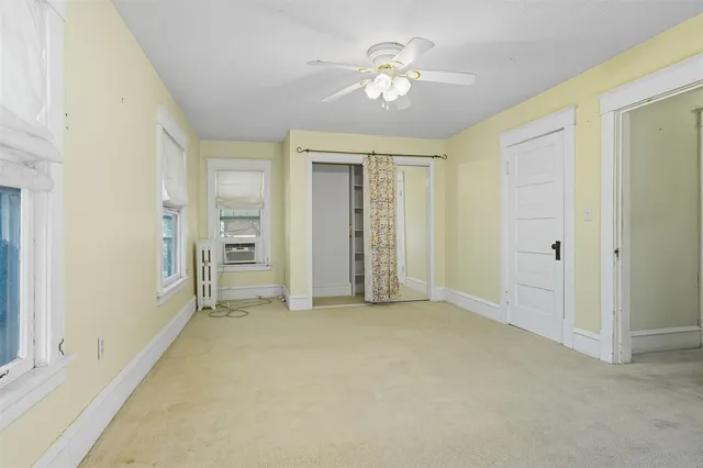 an empty room with chandelier fan and closet area