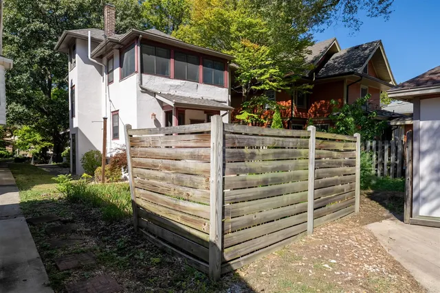a view of a house with a small yard plants and large tree
