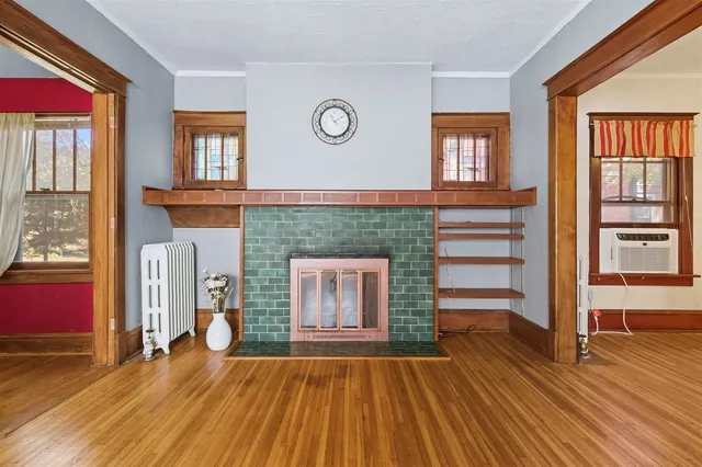 an empty room with wooden floor a fireplace and windows