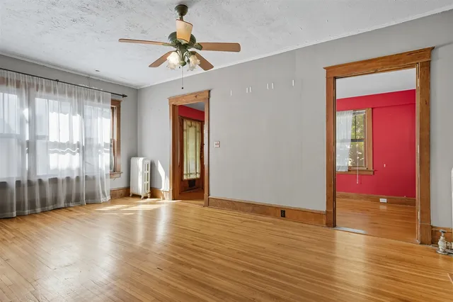 a view of an empty room with window and wooden floor
