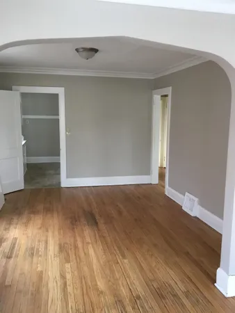 a view of an empty room with wooden floor and closet