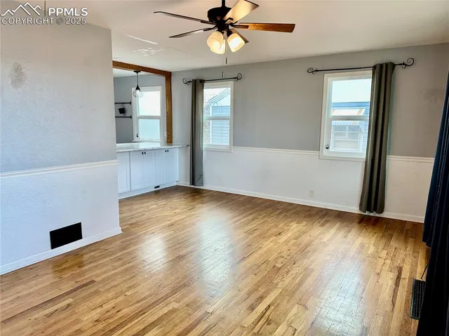 an empty room with wooden floor and windows