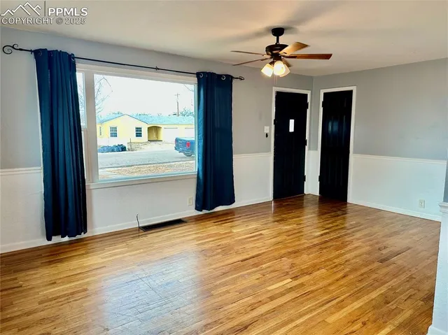 a view of an empty room with a window and wooden floor