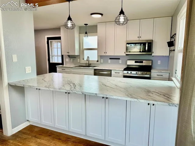 a kitchen with stainless steel appliances granite countertop a sink a stove and a wooden floors