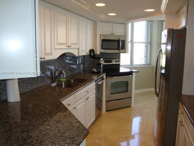 a kitchen with kitchen island granite countertop a stove a sink and a refrigerator