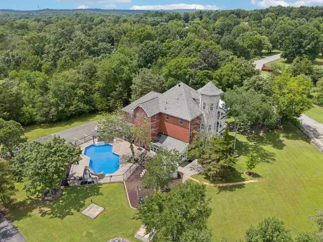 an aerial view of a house with swimming pool and outdoor seating