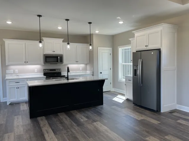 a kitchen with a sink a microwave a stove and a wooden floor