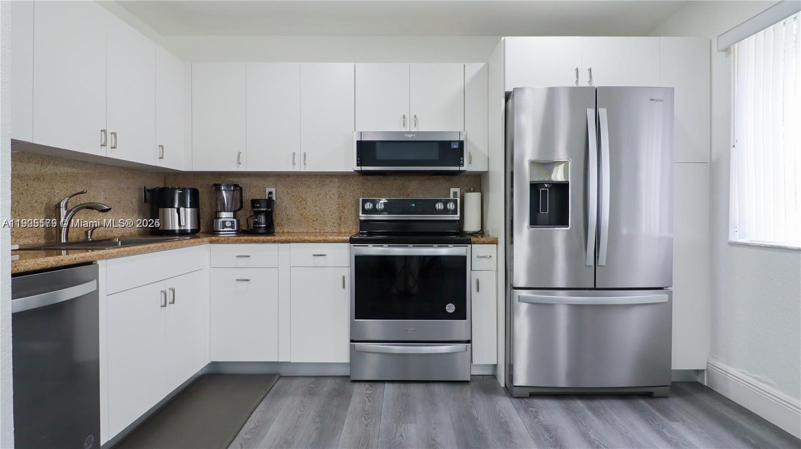 15330 Southwest 134th Place, Unit 308 Miami, FL 33177 - Photo 11 of 29 a kitchen with a refrigerator stove and white cabinets