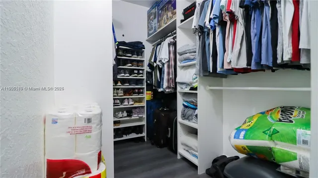 a view of walk in closet with clothes and shoes