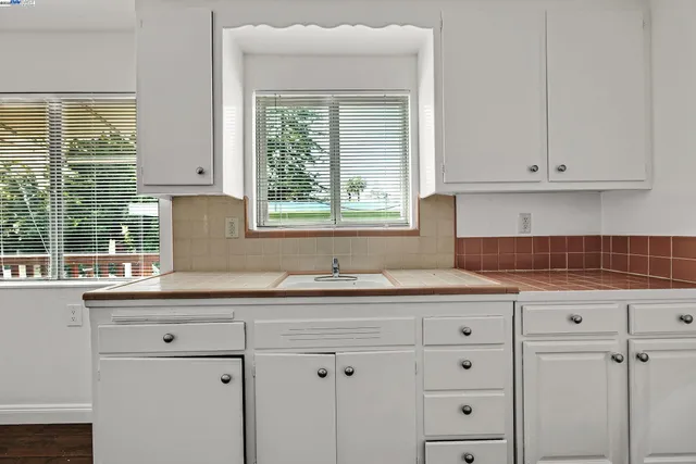 an empty room with wooden floor chandelier fan and windows