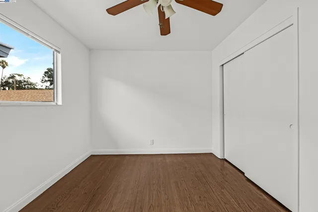 an empty room with wooden floor and a ceiling fan