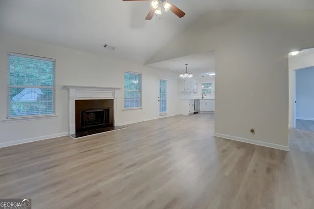an empty room with wooden floor fireplace and windows