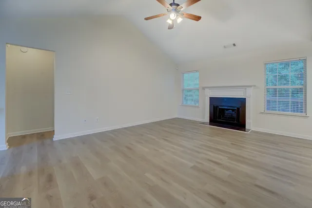 an empty room with windows fireplace and fan