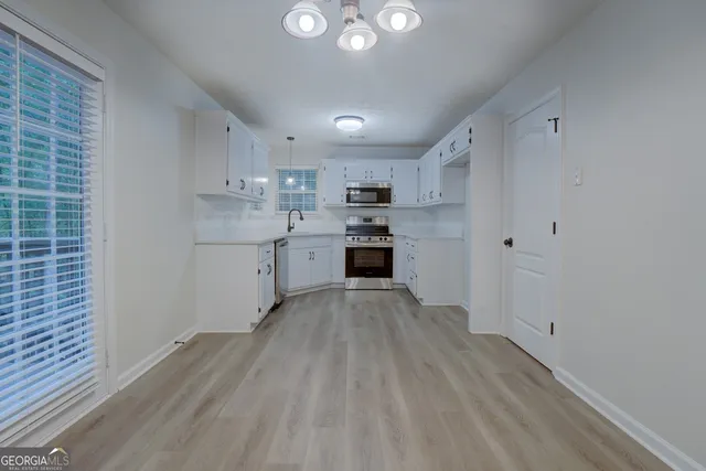 a kitchen with cabinets wooden floor and stainless steel appliances