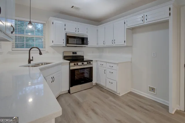 a kitchen with stainless steel appliances a white stove top oven and white cabinets