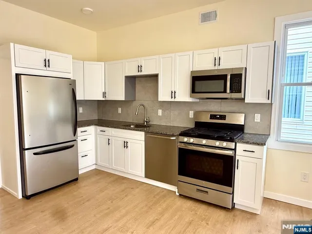 a kitchen with stainless steel appliances granite countertop a refrigerator stove a sink and a microwave