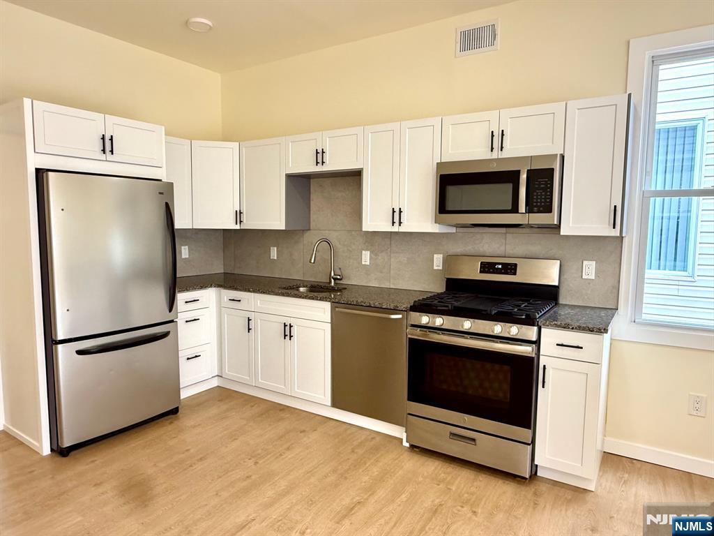 144 Centre Avenue Secaucus, NJ 07094 - Photo 1 of 22 a kitchen with stainless steel appliances granite countertop a refrigerator stove a sink and a microwave