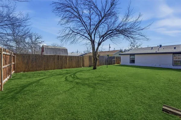 a view of house with a big yard and large trees