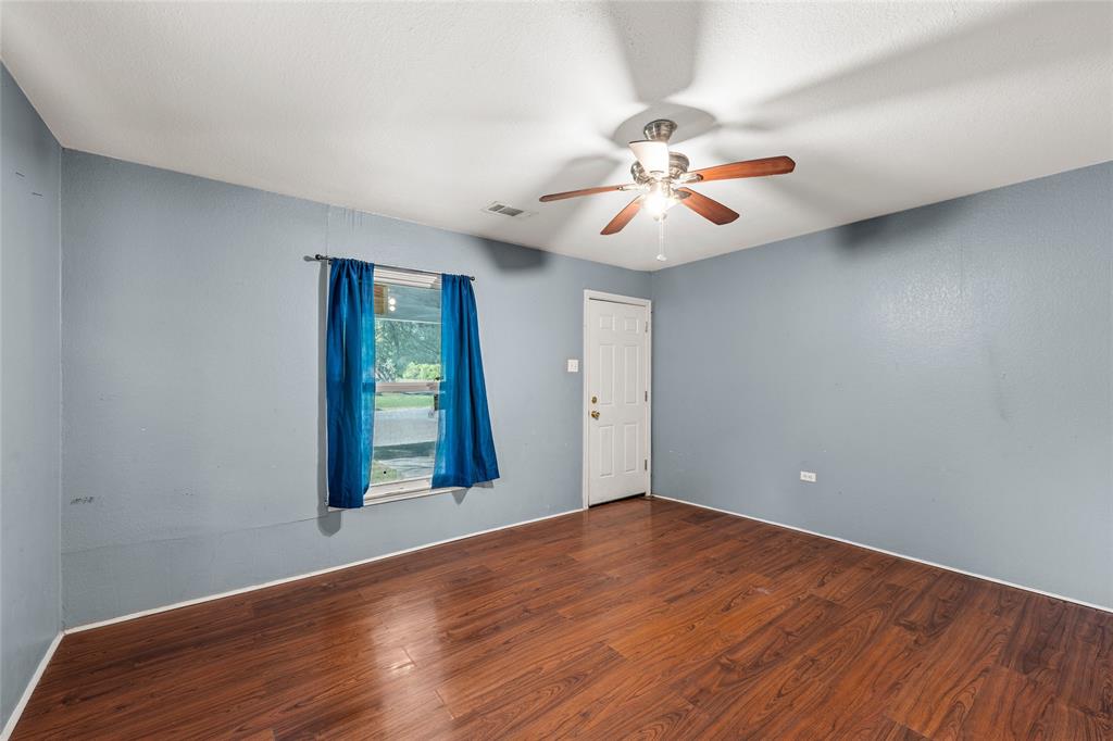 2225 Mitchell Avenue Waco, TX 76708 - Photo 12 of 16 Interior room featuring wood-finish flooring, a ceiling fan with integrated lighting, a window, and a paneled door