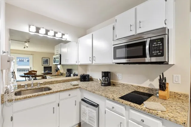 a kitchen with granite countertop white cabinets and white appliances