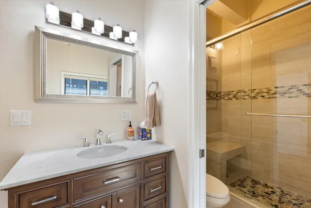 a bathroom with a granite countertop sink toilet and shower