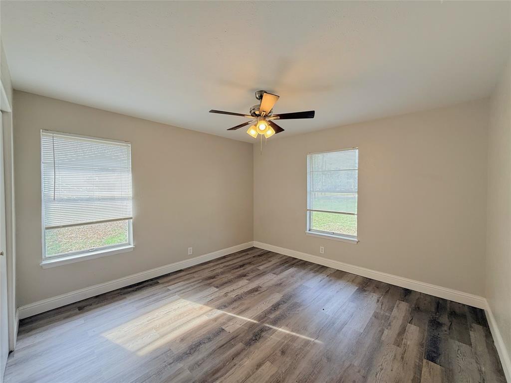 4075 Old Bonham Road Paris, TX 75460 - Photo 17 of 20 an empty room with wooden floor chandelier fan and windows
