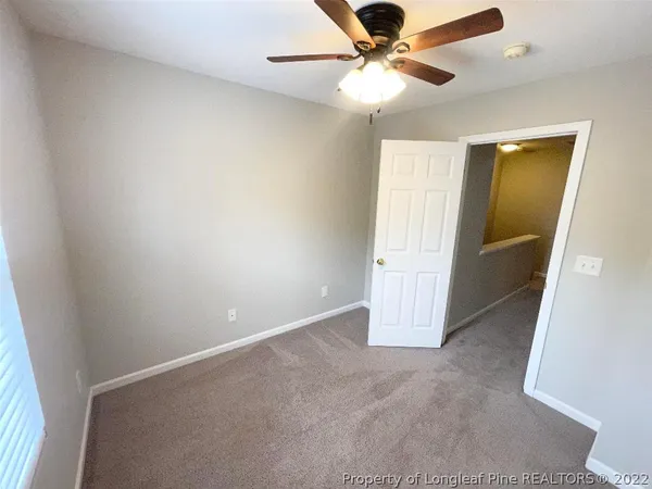 an empty room with a ceiling fan and carpet