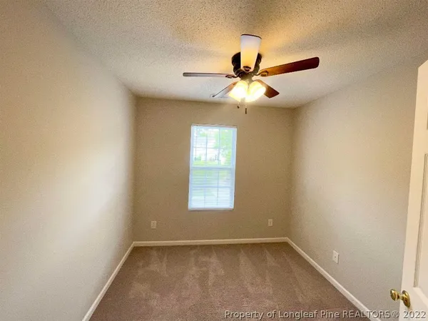 an empty room with windows and fan