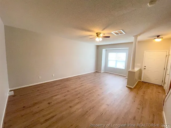 an empty room with wooden floor and windows