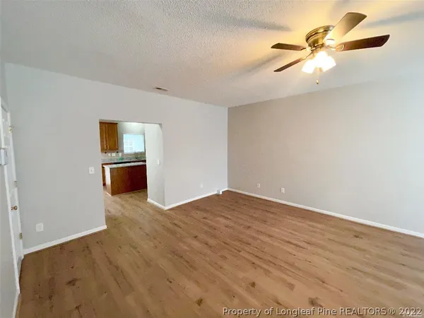 an empty room with wooden floor fan and windows