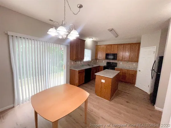 a kitchen with stainless steel appliances granite countertop a refrigerator a sink dishwasher a stove and white countertops with wooden floor