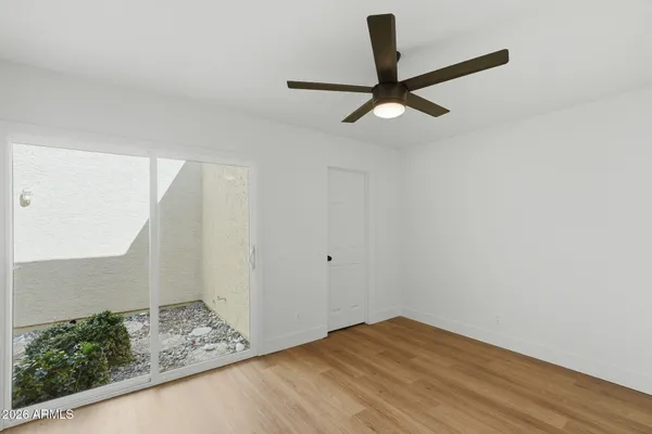 a view of empty room with wooden floor and ceiling fan
