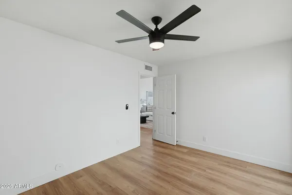 an empty room with wooden floor and ceiling fan